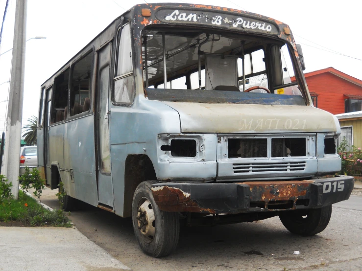 an old rusted and run down bus sits near the curb