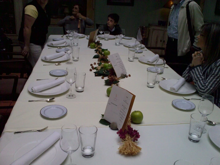 tables are lined up with white clothed plates and napkins