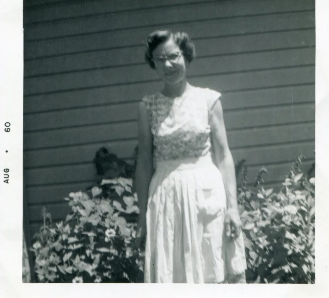 a woman in white dress standing by flowers