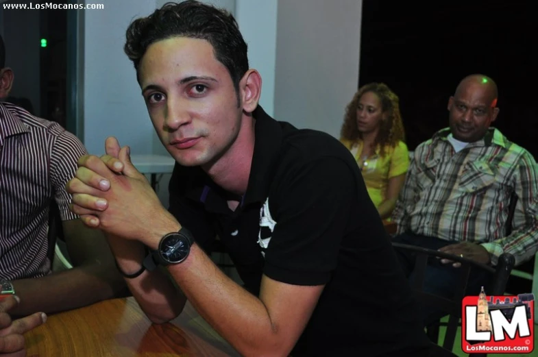 a young man sitting at a table with a wrist watch