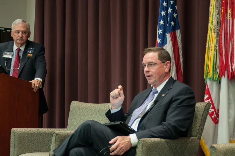 a man is sitting in a chair while speaking