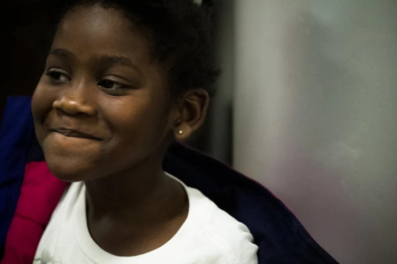 a child smiling in a room with wall and doorway