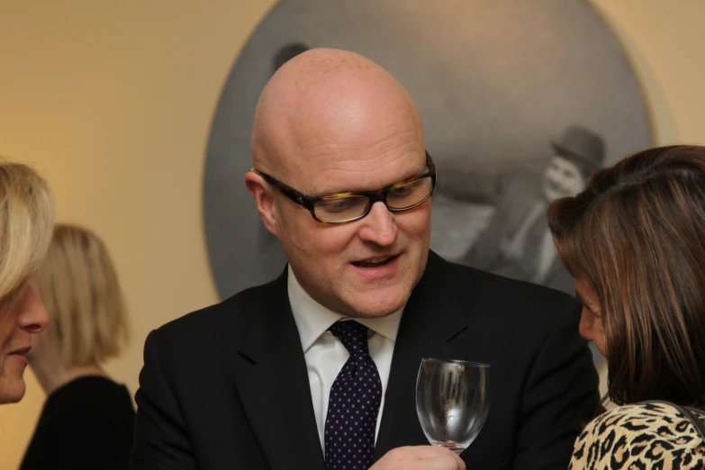 a man in a suit talks with two ladies