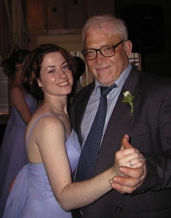 an elderly man and woman pose for a po in front of other people