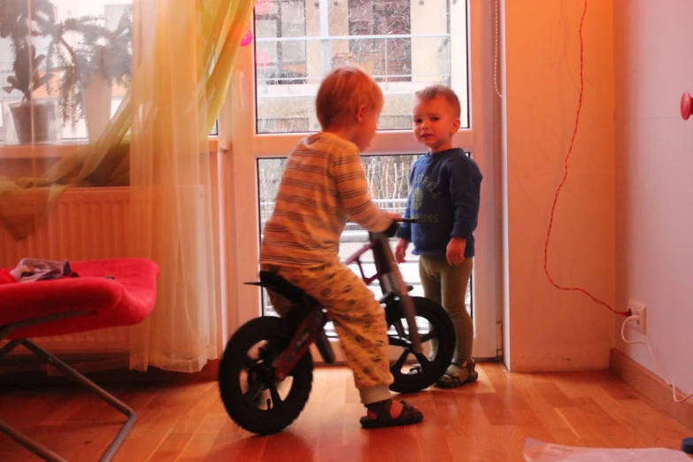 two boys on bikes in the house looking out the window
