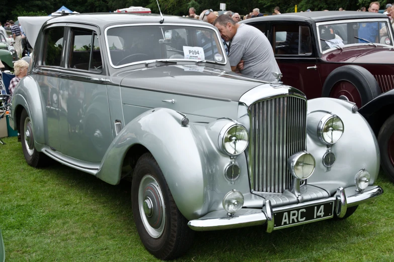 a man examines the side of an old fashion car