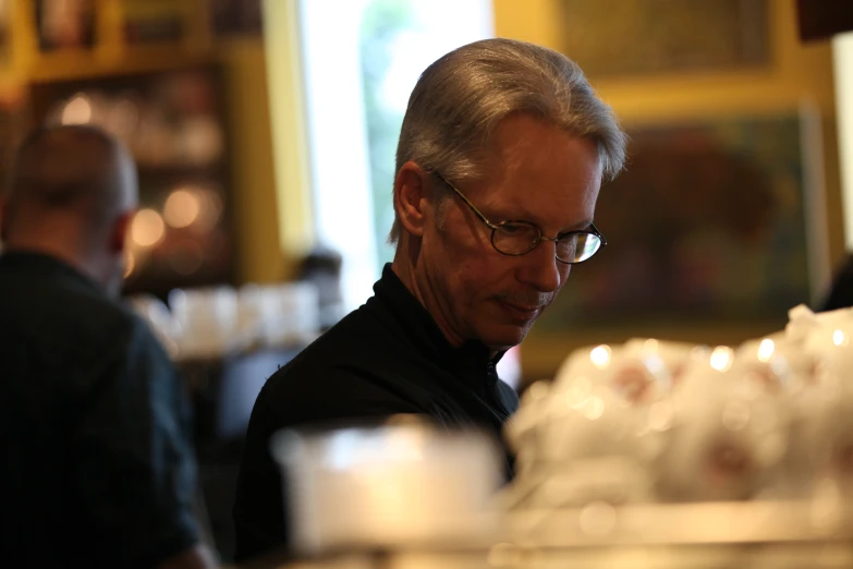 a man in a black shirt with glasses on looking at soing