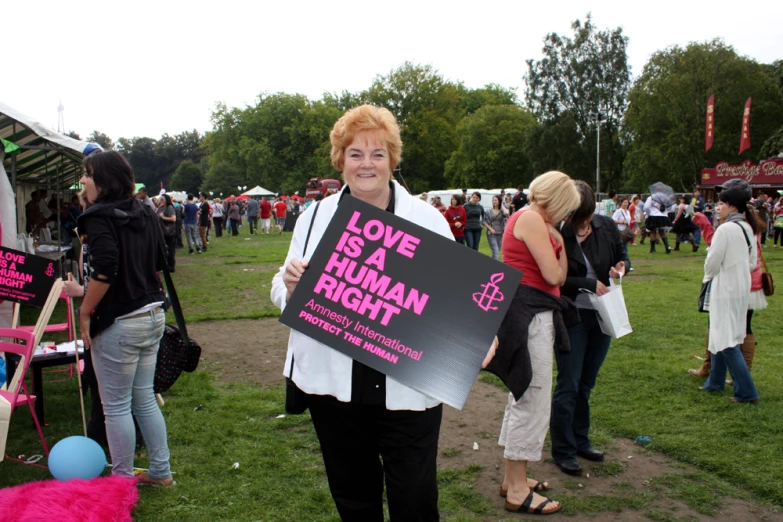 woman in white shirt carrying pink protest sign