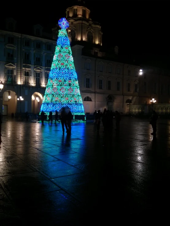 a very big lit up christmas tree in the middle of a square