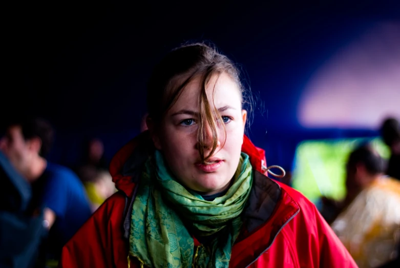 a girl wearing a red jacket and scarf looking out