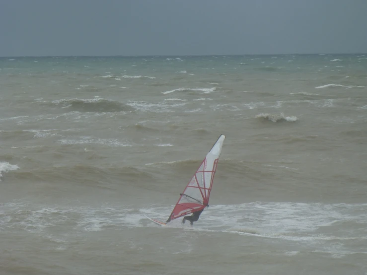 a person windsurfing on the beach on a cloudy day