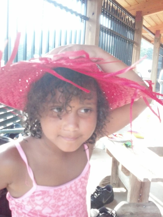 young child with pink dress and a hat standing outside