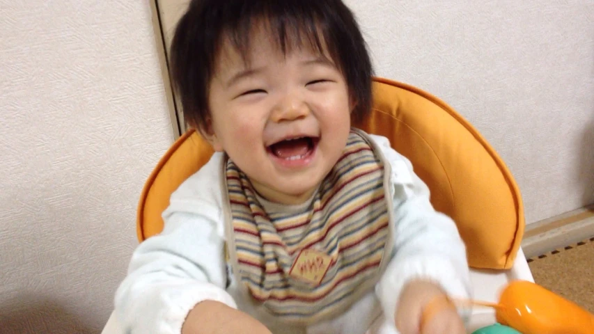 a young  sitting in a high chair with orange plastic cups