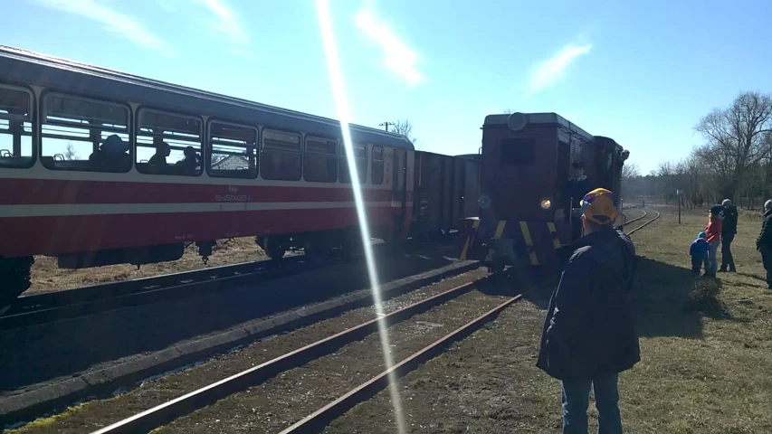 a man in yellow safety vest standing by a red and white train