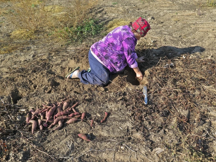 a person laying down in the dirt holding a knife
