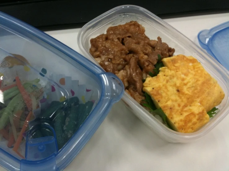 two plastic containers sitting on a counter with food