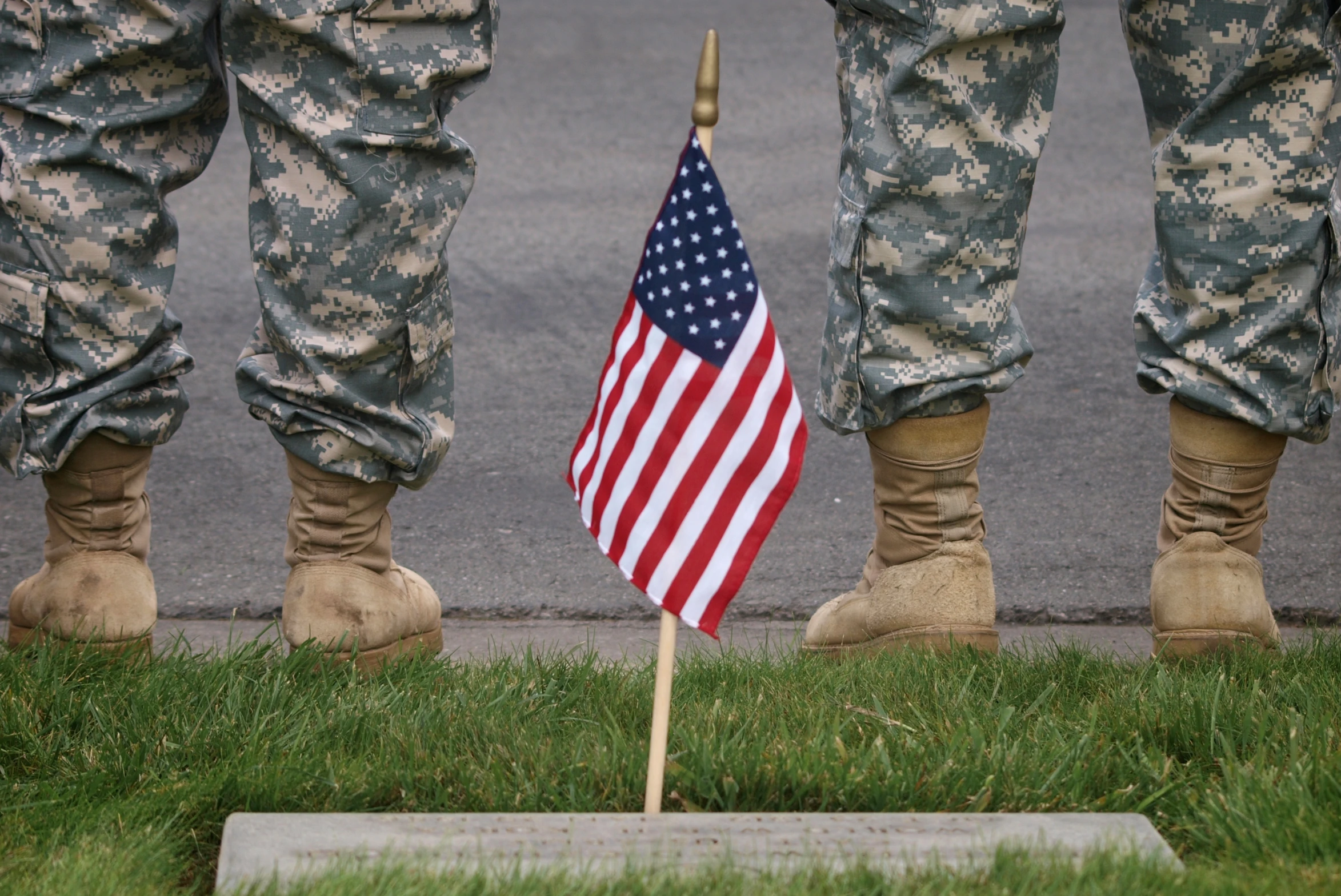 three soldiers with legs in boots are holding american flags