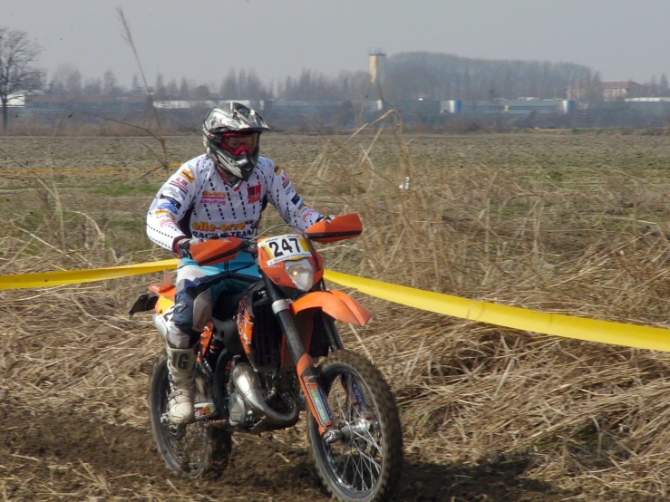a man riding an orange motorcycle through a field