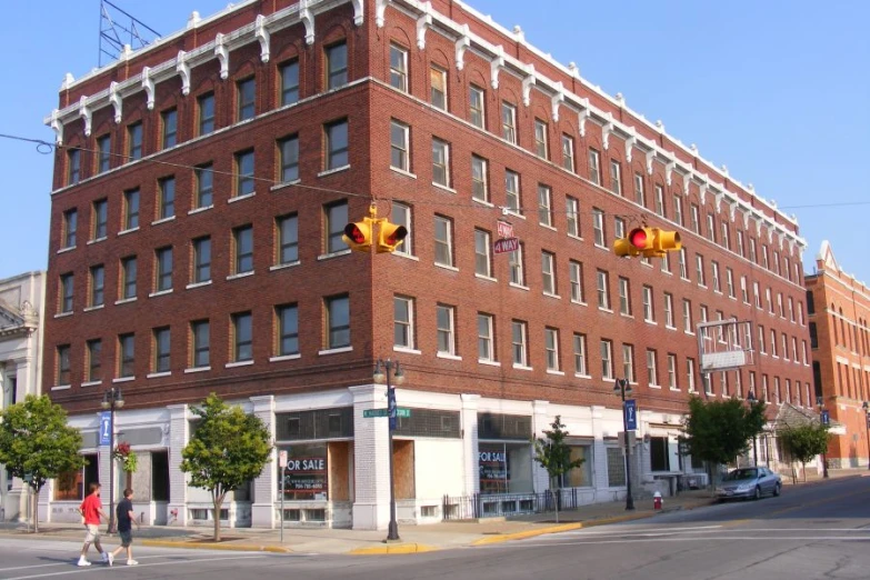 a large red brick building is seen at an intersection