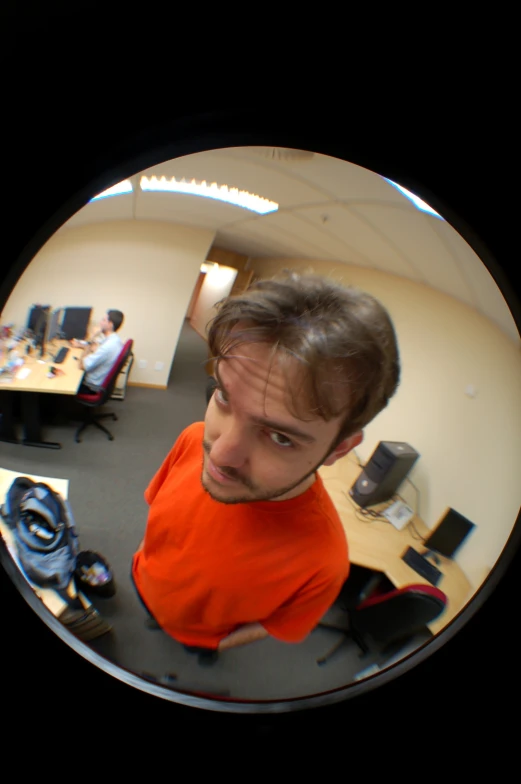 man in an orange shirt in a round camera lens