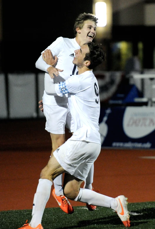 two male soccer players are playing soccer on the field