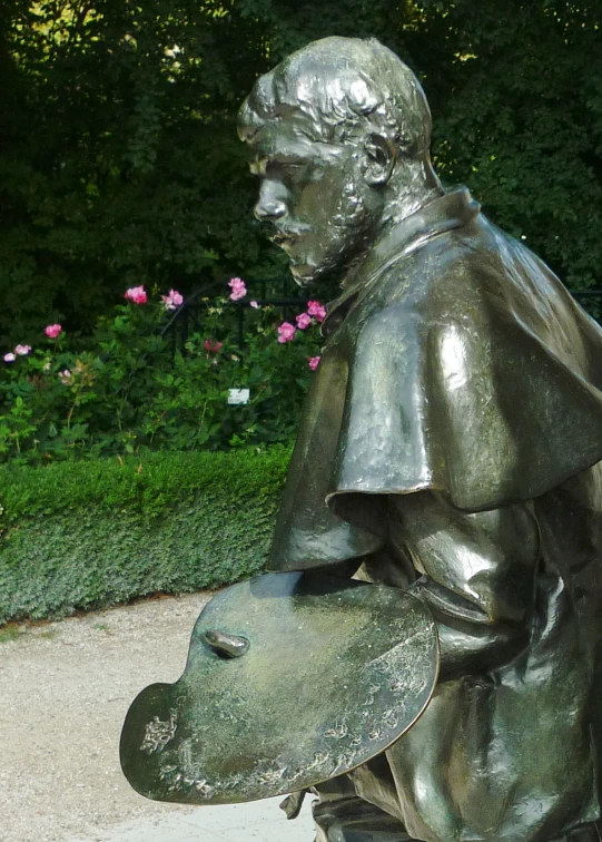 a sculpture with a leafy plant and small bushes in the background