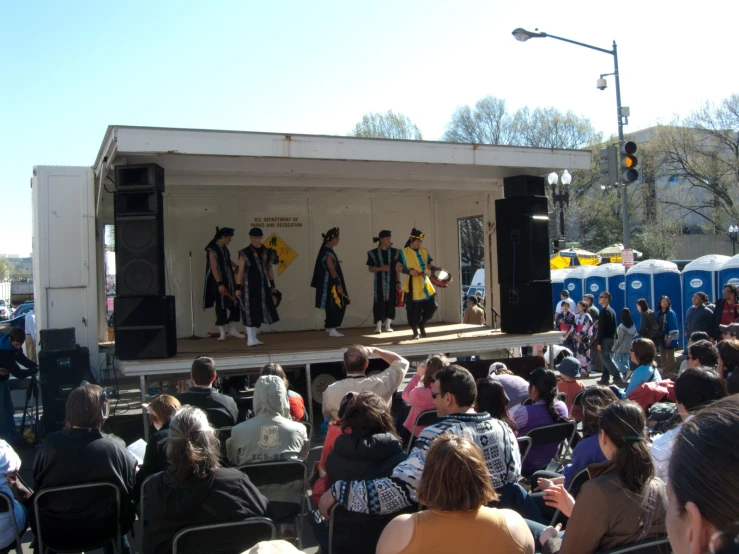 some people in chairs on a stage watching some music