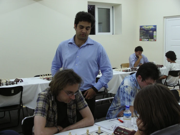 a man playing chess at a party in front of other people