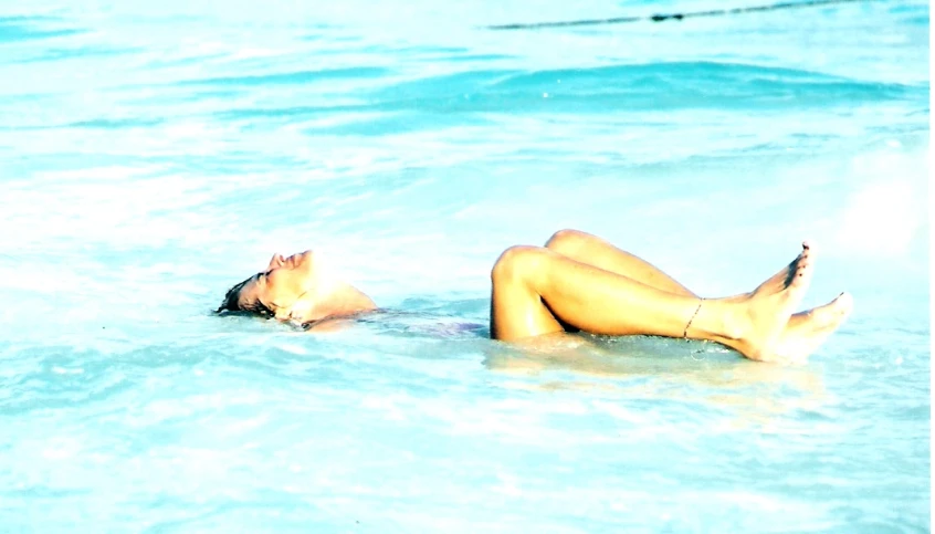 a woman laying in the ocean on her stomach