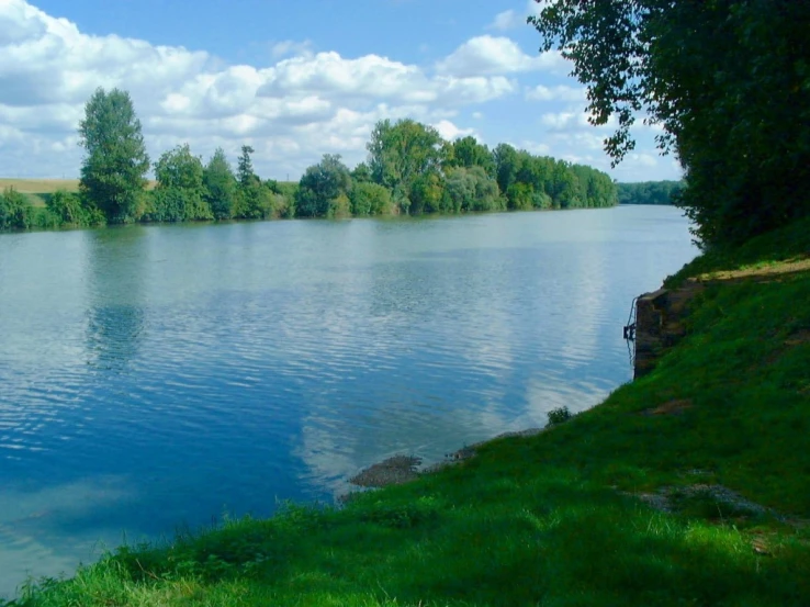 a calm lake sits empty with green grass on both sides