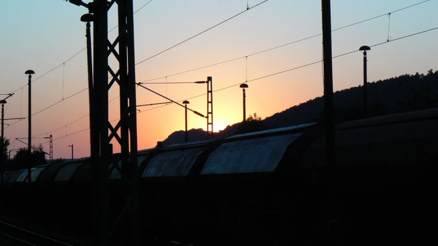 a train passing by some power lines and mountains