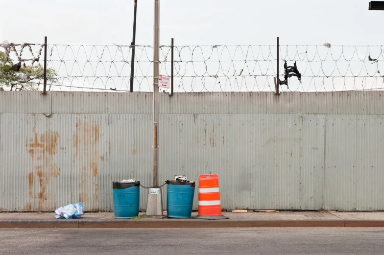 a fence that is next to some trash containers