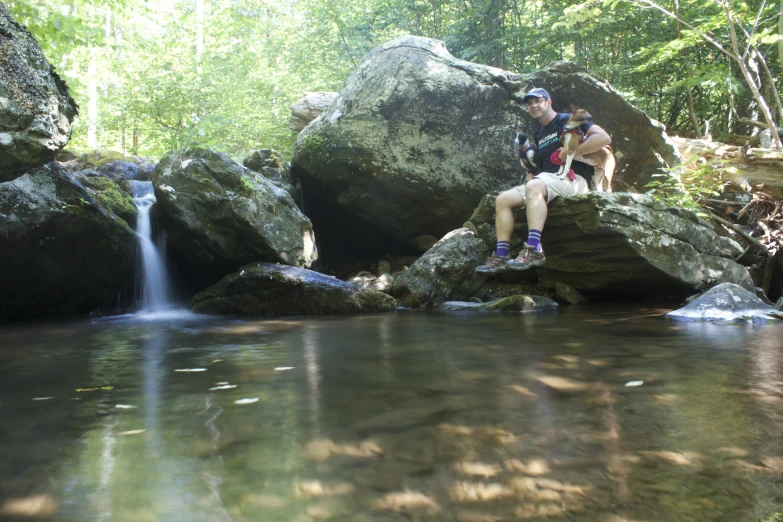 a man sitting on top of rocks near a water fall