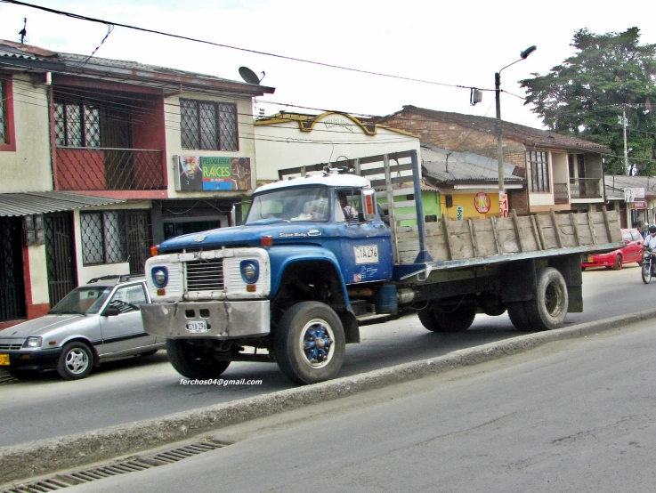 a blue dump truck driving down a street