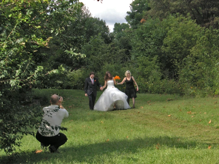 a woman in a white wedding dress walking with two men