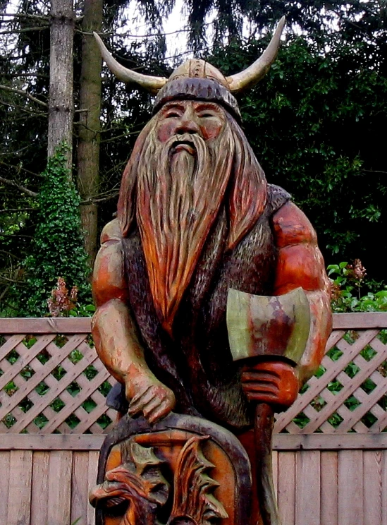 a wooden statue in a yard wearing a horned costume