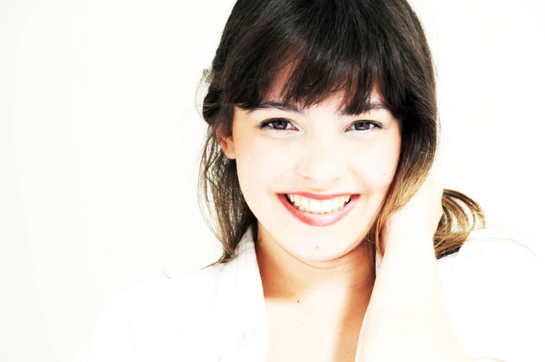 a woman smiling wearing a white shirt and a brown band around her neck