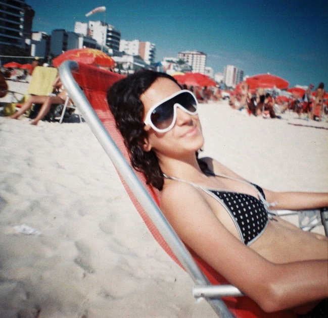 a woman sitting on top of a beach near some umbrellas