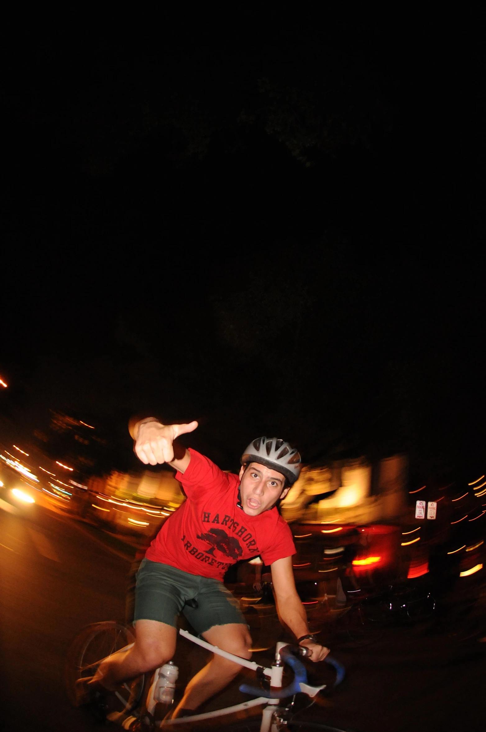 guy riding bike at night with headlights in the background