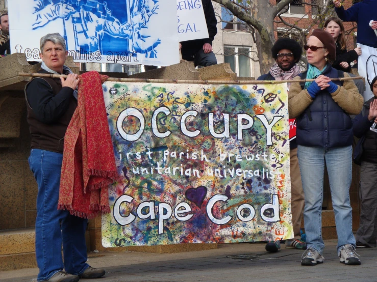 people stand in line behind a protest sign