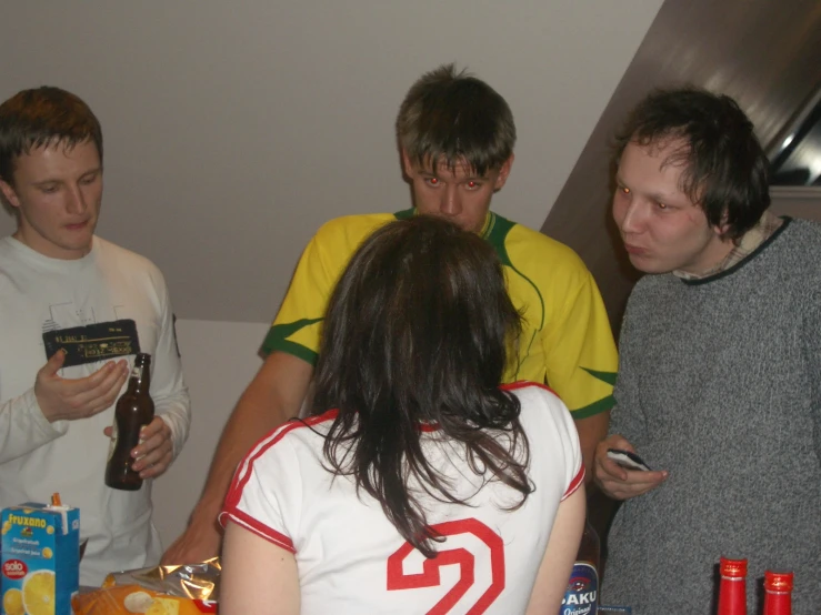 three young men standing around one another with beer in their hands