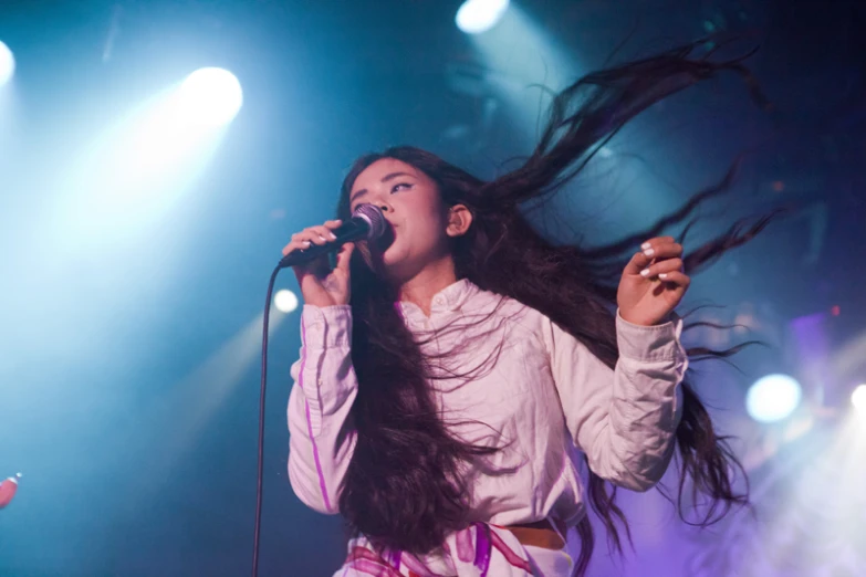 the woman is holding her hair up while singing on stage