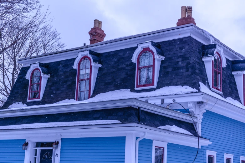 two windows on top of a blue house with snow