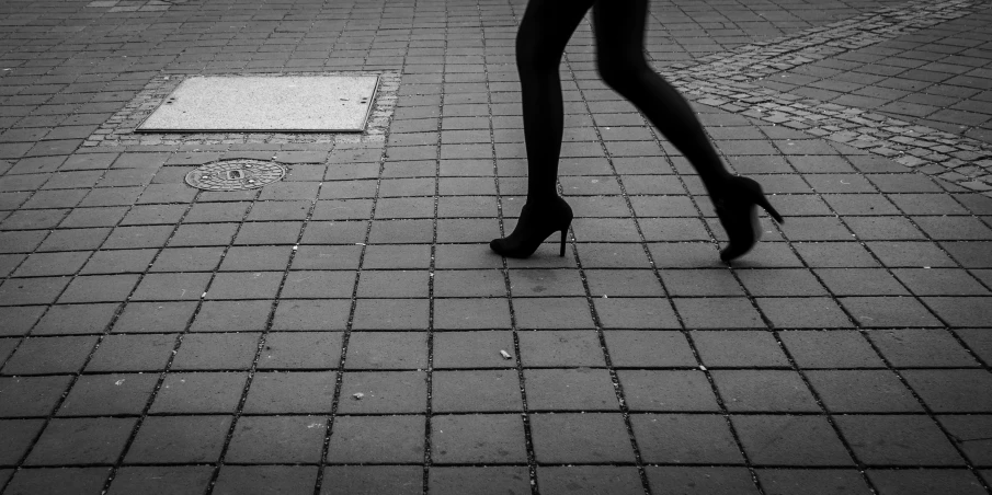 a woman is walking down the sidewalk in high heels