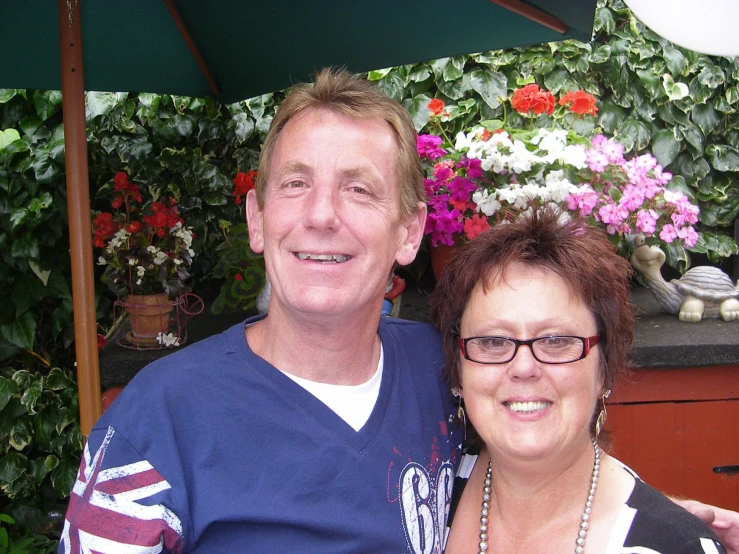 two people standing under an umbrella posing for the camera