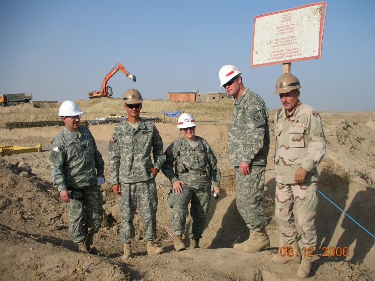 military men in hard hats stand outside in the desert