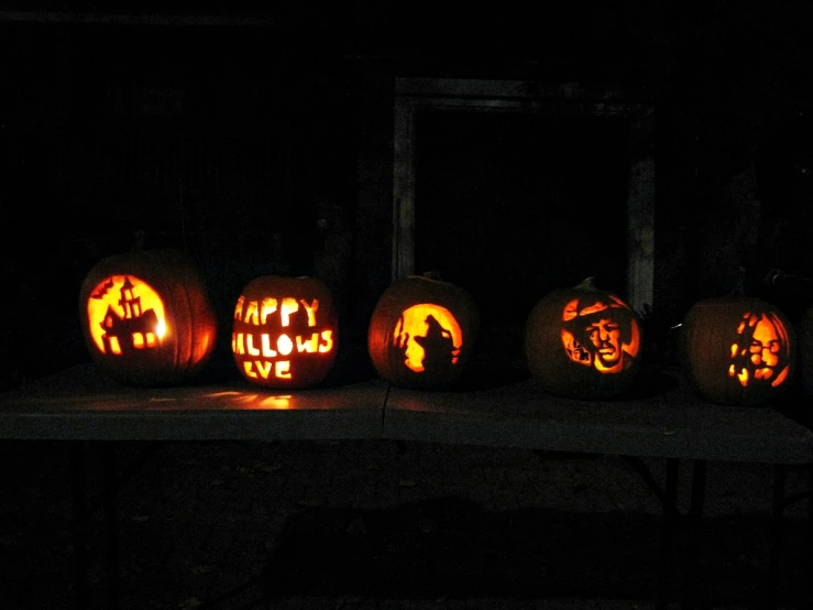 lighted pumpkins sitting in the dark with faces carved onto them
