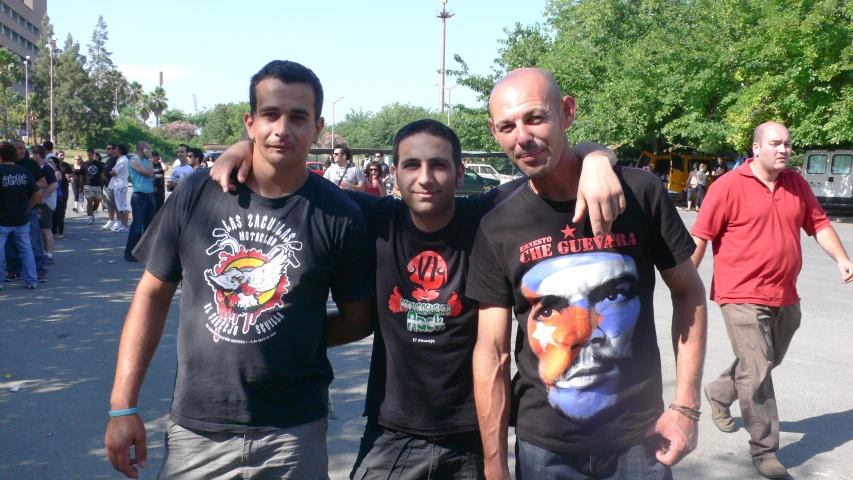 three men standing next to each other on the side of a road