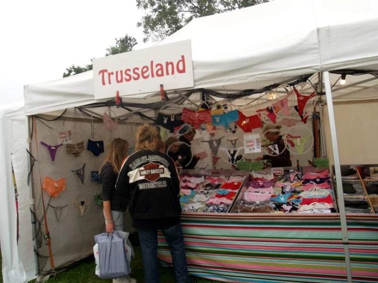 people standing in front of a tent near other items