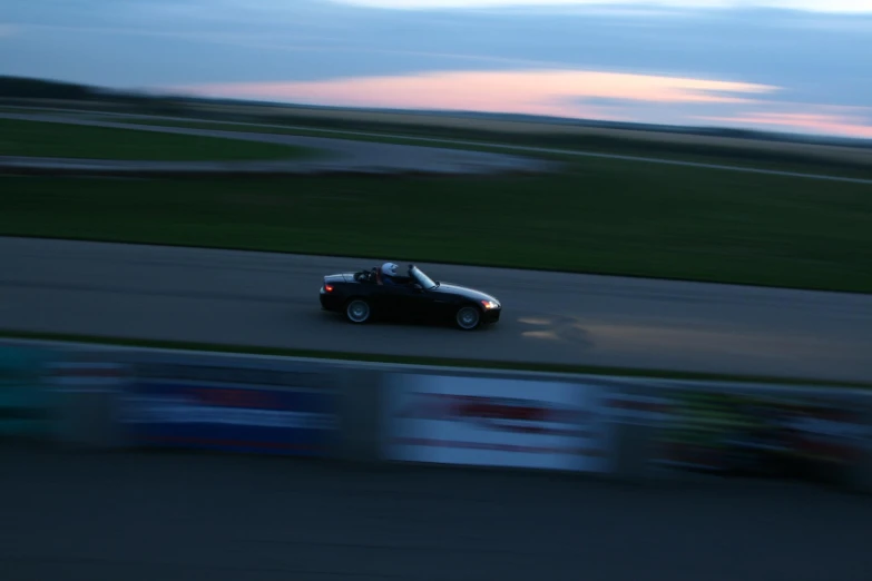 a car driving down a race track at dusk